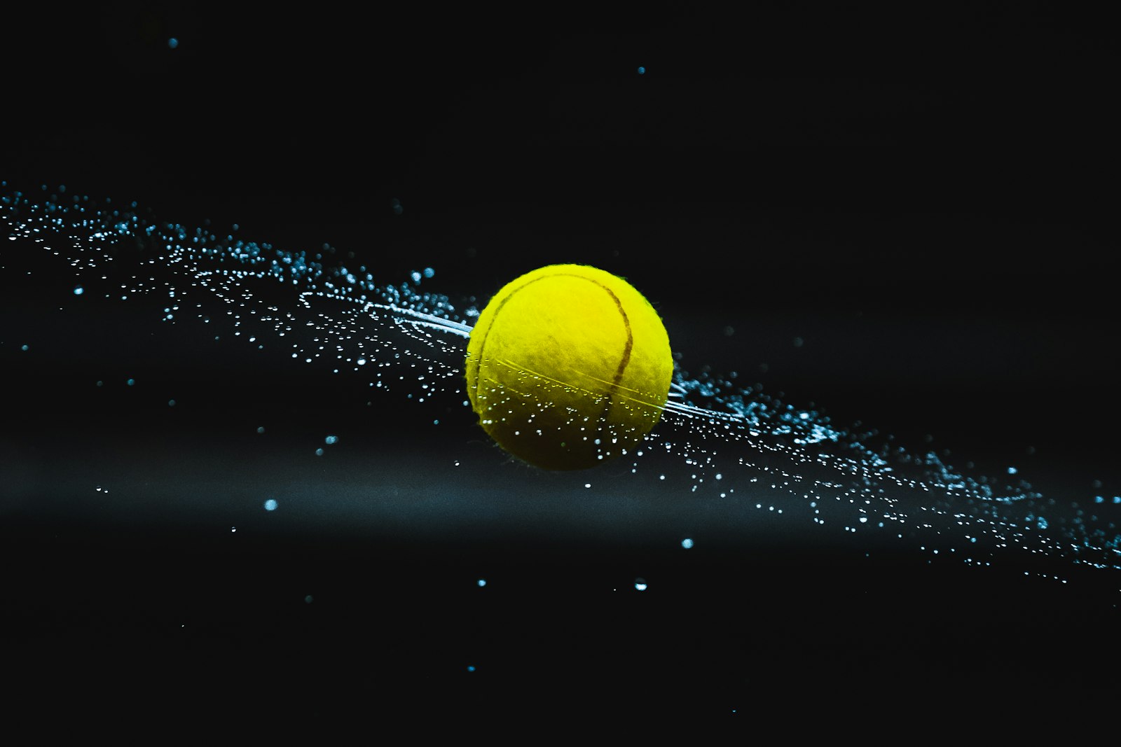 Tennis ball cutting through the dark, trailing spray